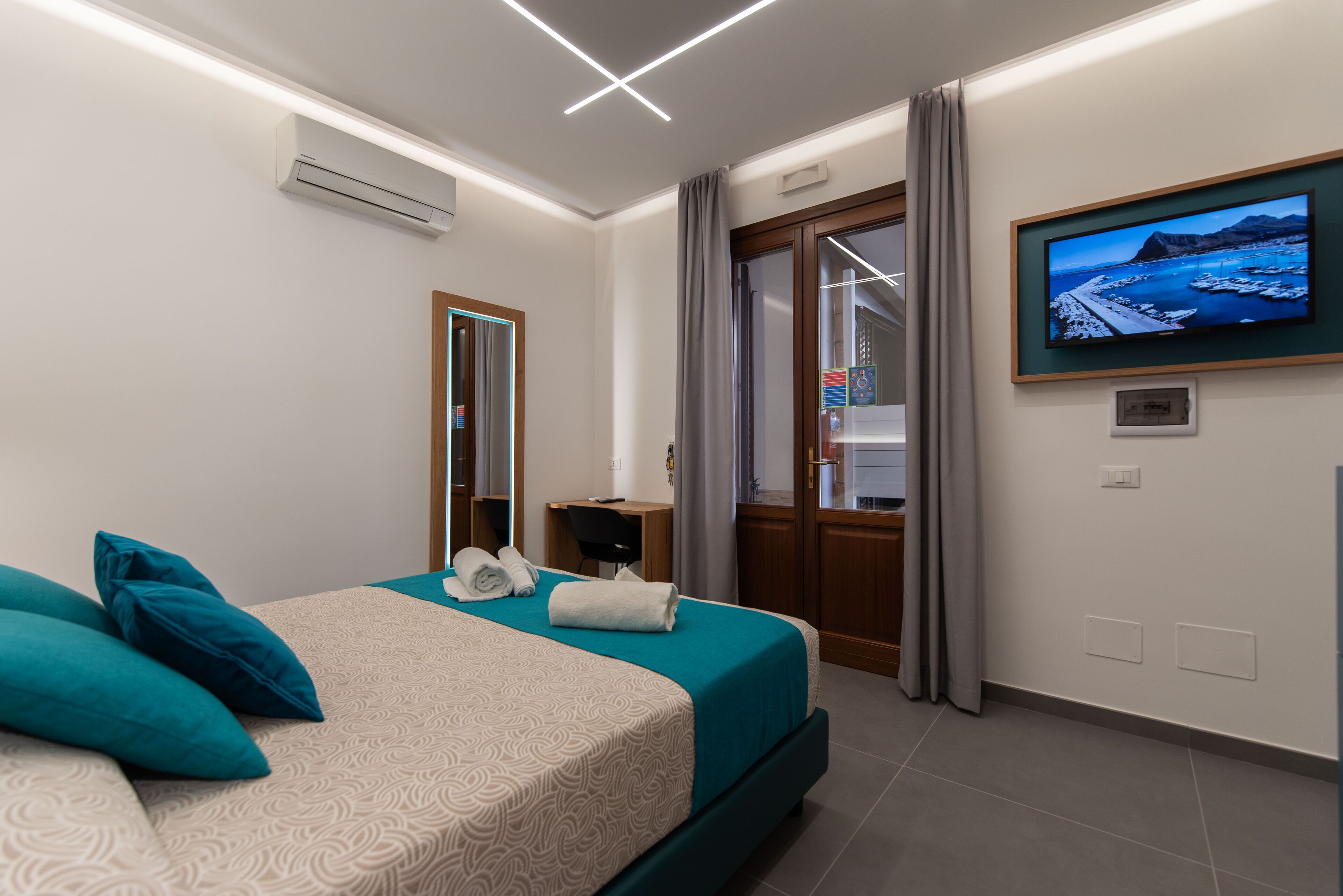 Ein modernes Hotelzimmer mit einem Bett, einem Schreibtisch und einem an der Wand befestigten Fernseher.