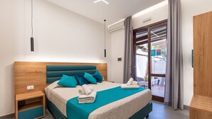 A modern bedroom with a teal bedspread, wooden headboard, and a nightstand with a drawer. - Room & Breakfast Aloe (San Vito Lo Capo)