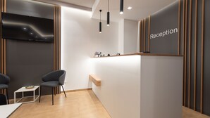 A reception area with a modern design, featuring a reception desk, seating area, and a flat-screen TV. - Room & Breakfast Aloe (San Vito Lo Capo)