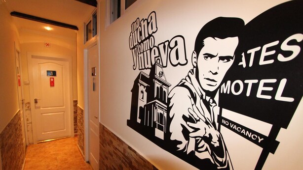 A hotel hallway with a wall advertisement featuring a man and a building, and a sign indicating no vacancy.