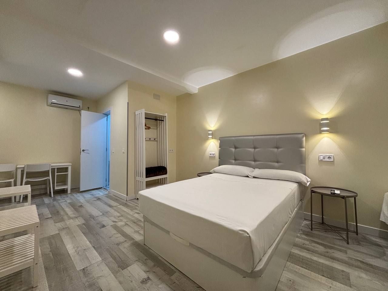 Ein Schlafzimmer mit einem Bett, Nachttischen, einem Schreibtisch und einem Kleiderschrank.