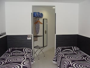 A hotel room with two single beds, a wardrobe, a mirror, and a small shelf with toiletries. - Hostal JQ Madrid 1 (Madrid)