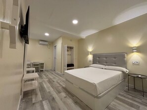 A hotel room with a bed, bedside table, wall-mounted TV, and a small table with a chair. - Hostal JQ Madrid 1 (Madrid)