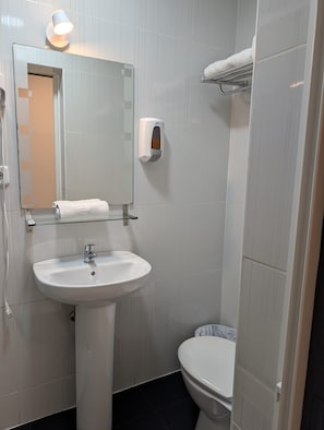 A bathroom with a white sink, a mirror, a toilet, and a towel rack. - Hostal JQ Madrid 1 (Madrid)