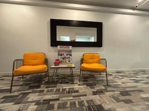 A room with two yellow chairs, a small table, and a bulletin board with various items. - Hostal JQ Madrid 1 (Madrid)