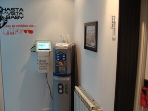 A room with a wall-mounted iPad charging station, a water dispenser, and a framed picture. - Hostal JQ Madrid 1 (Madrid)
