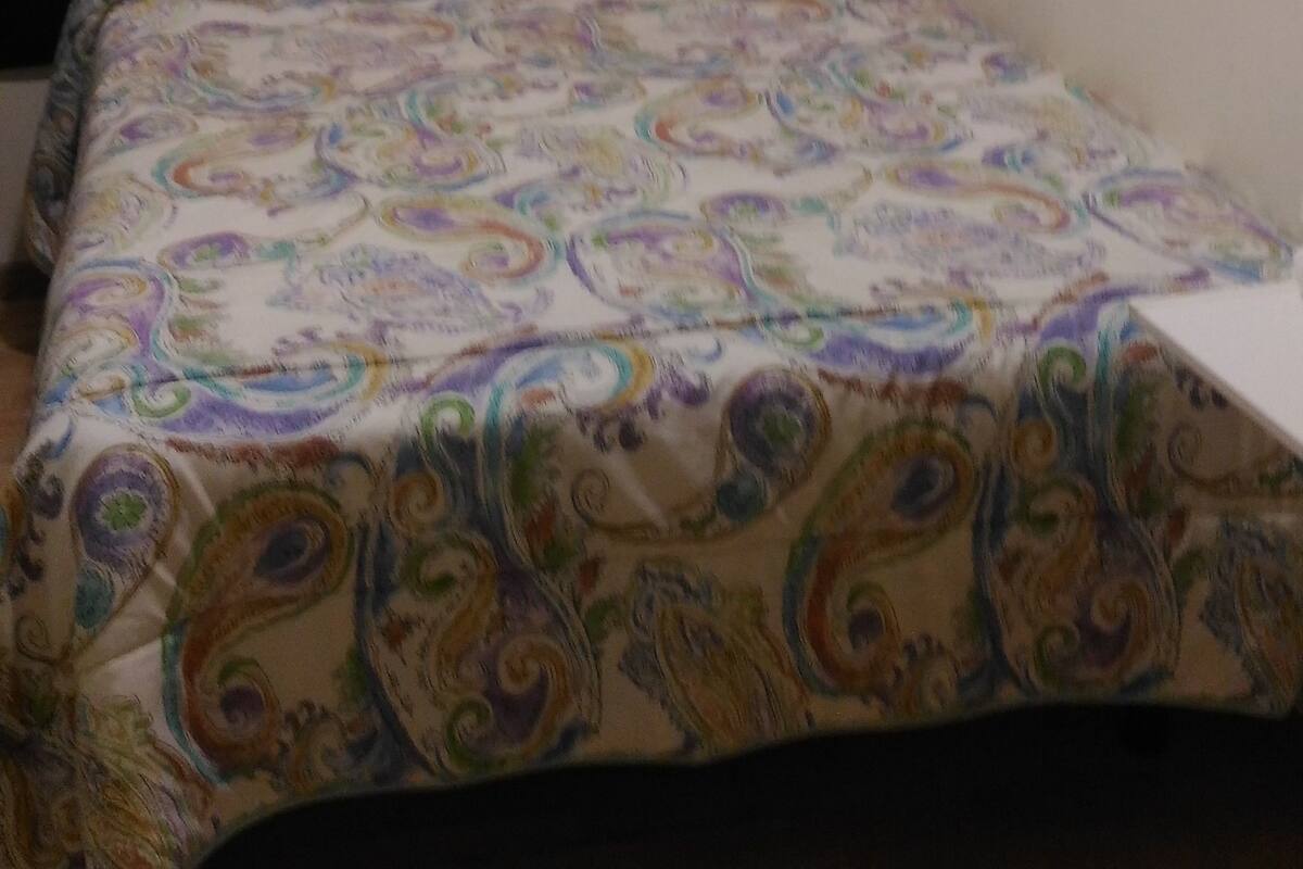 A room with a bed, curtains, an air conditioning unit, and a shelf with a decorative item.