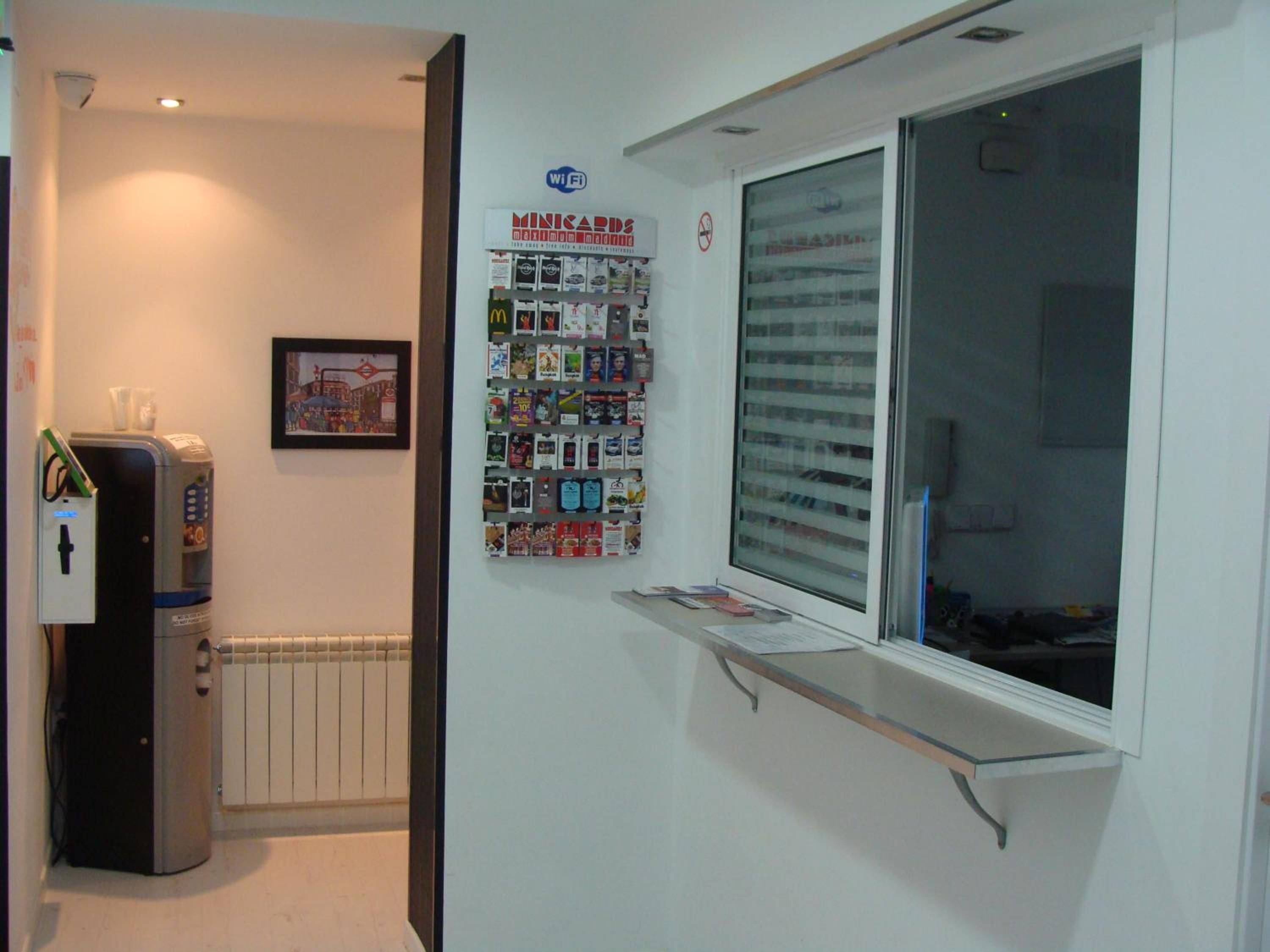 Una habitación con un radiador, un cartel en la pared, una ventana con vistas y un pequeño estante.