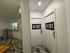 A hallway with doors labeled 101 and 102, a small kitchenette area, and a patterned floor. - Hostal JQ Madrid 1 (Madrid)