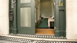 A hotel entrance with a check-in counter, a reception desk, and a staircase leading to the lobby. - BeiRoom Hyde Park Apartments (London)