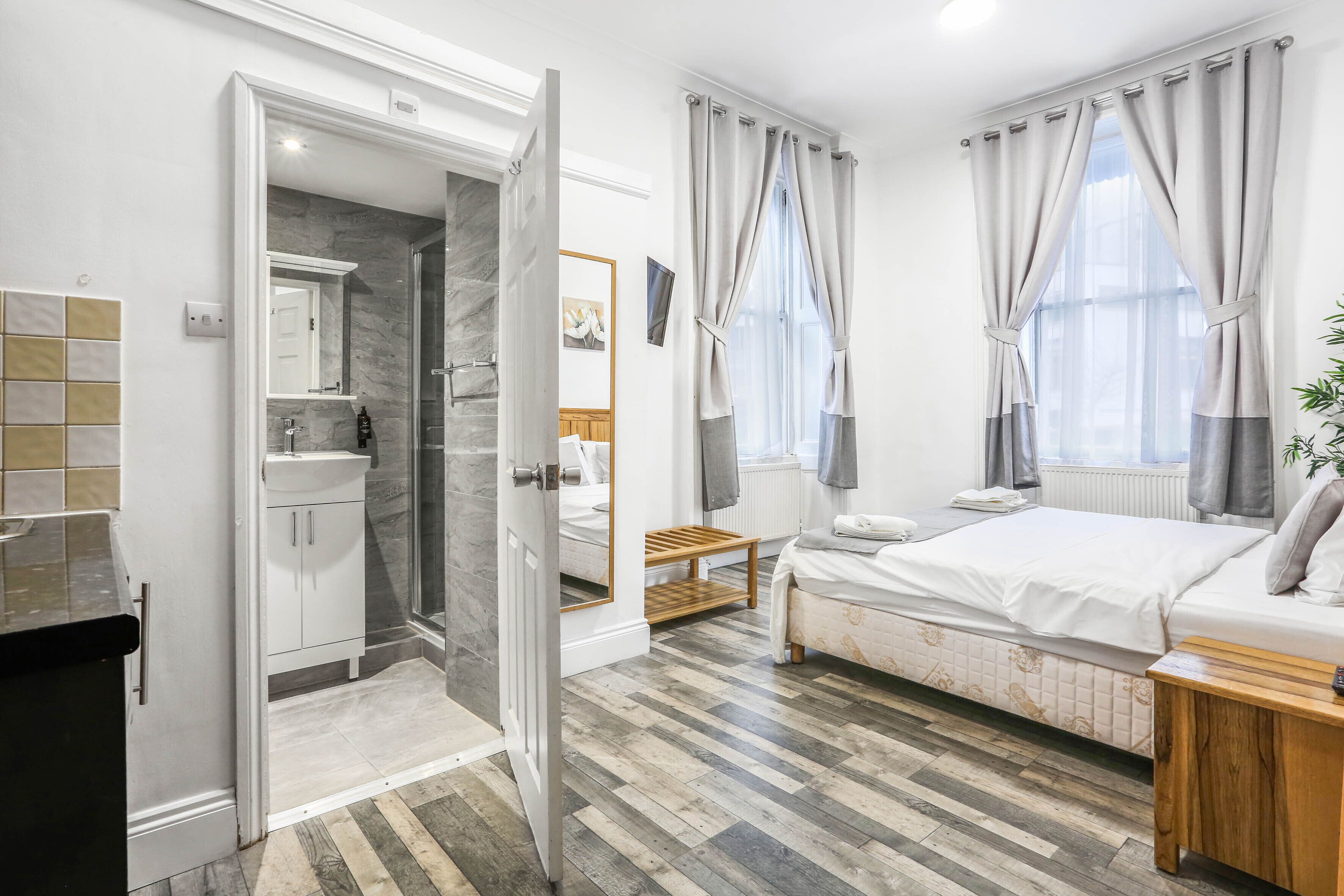Une chambre moderne avec un lit, une table de chevet et une salle de bain équipée d’une douche et d’un lavabo.