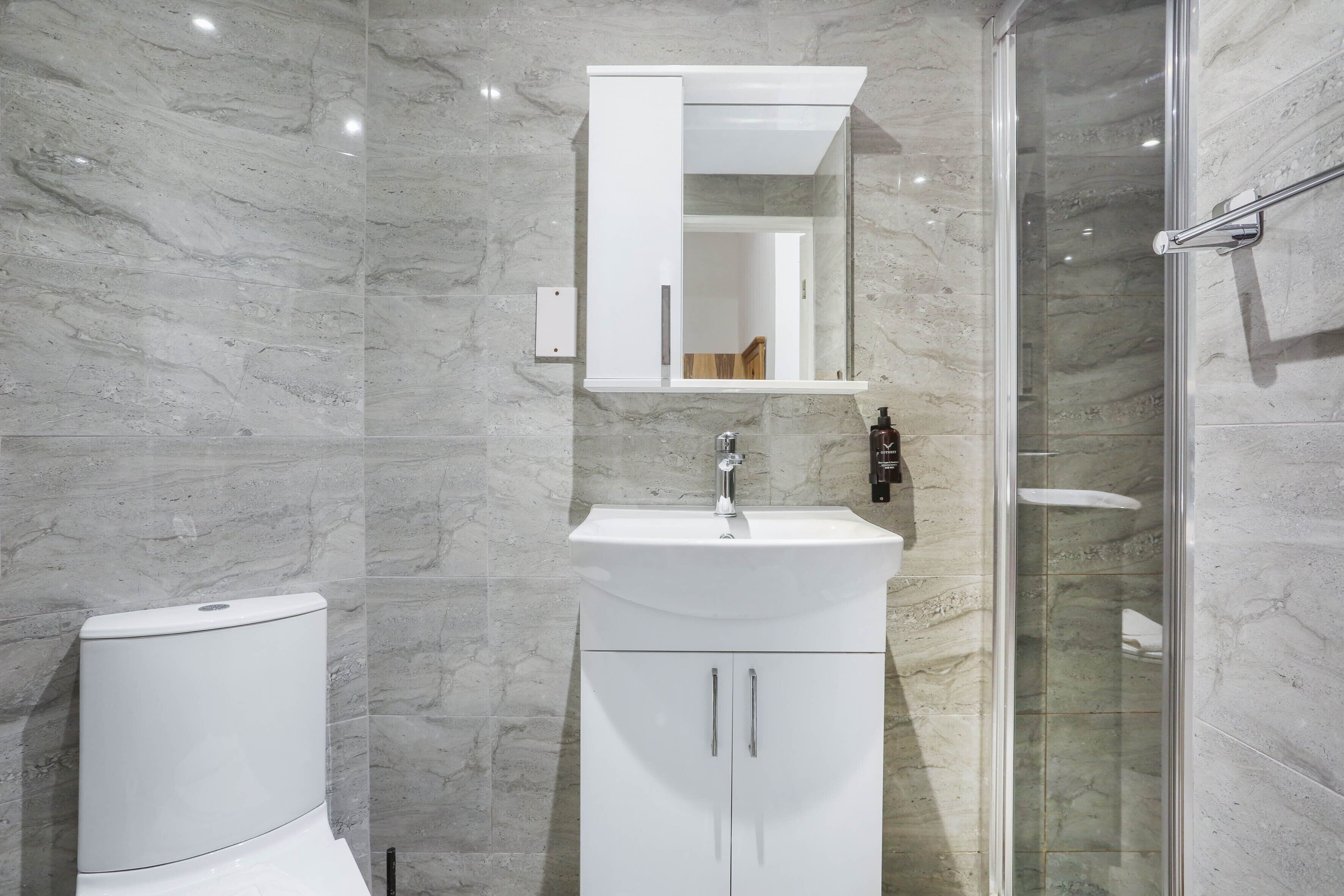 Ein modernes Badezimmer mit Toilette, Waschbecken mit Spiegel und einer Duschkabine.