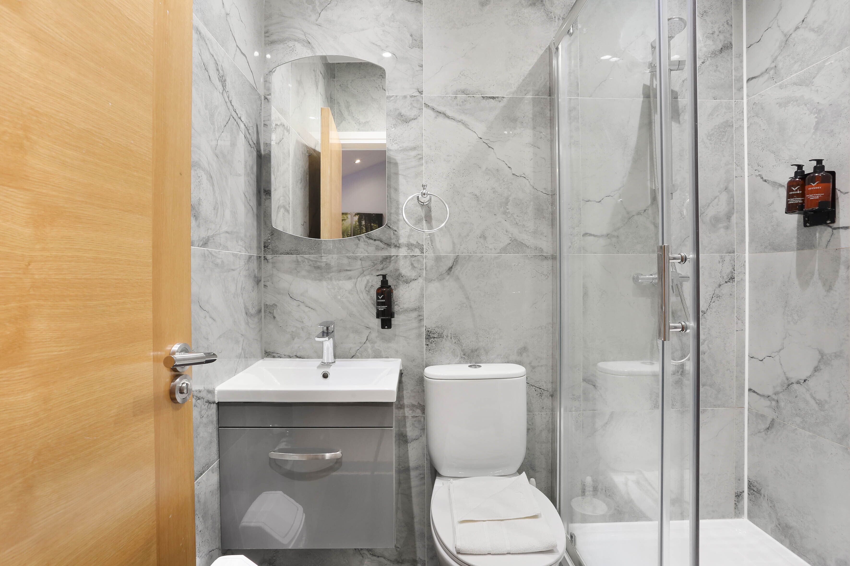 A modern bathroom with a marble sink, toilet, and glass shower enclosure.