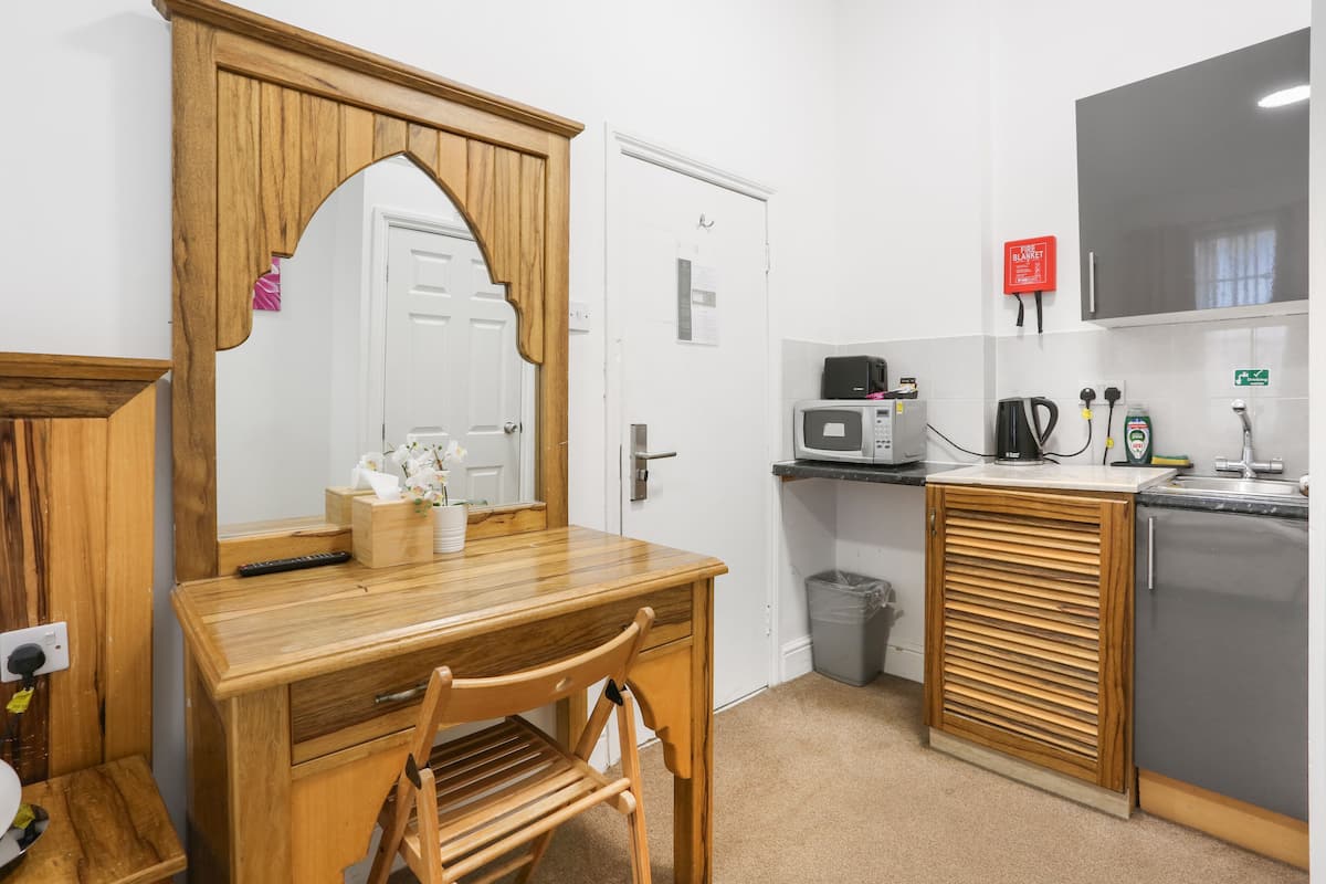 Een compacte keuken met een houten eettafel, een magnetron en een kleine koelkast.