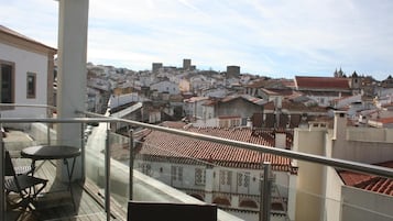 Un balcón con vista a una ciudad densamente poblada, que presenta arquitectura tradicional y un cielo despejado.