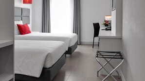 A modern hotel room with two beds, a desk, and a chair. - Rossio Hotel (Portalegre)