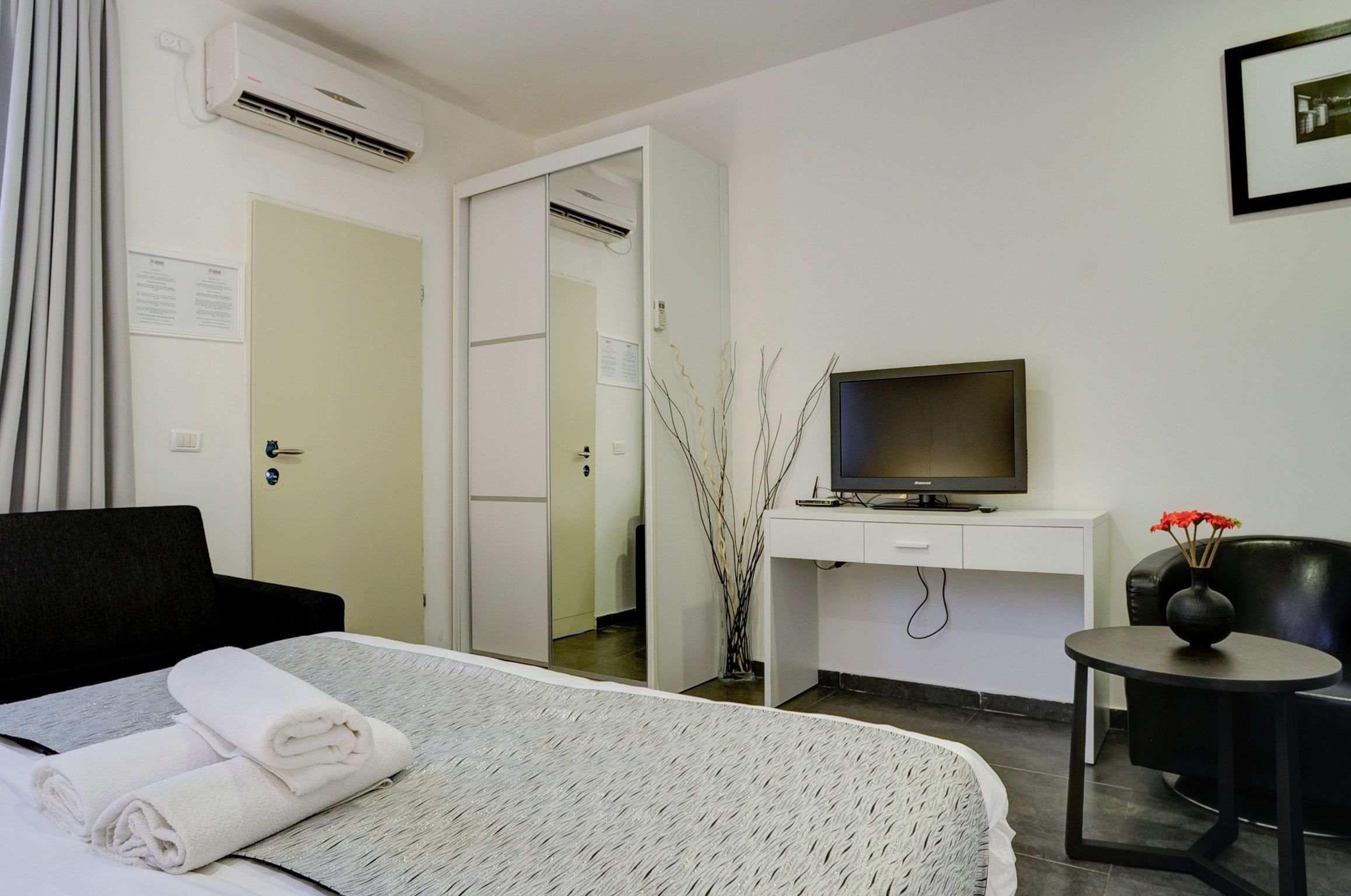 Una habitación de hotel con una cama, un escritorio, un televisor y una silla.