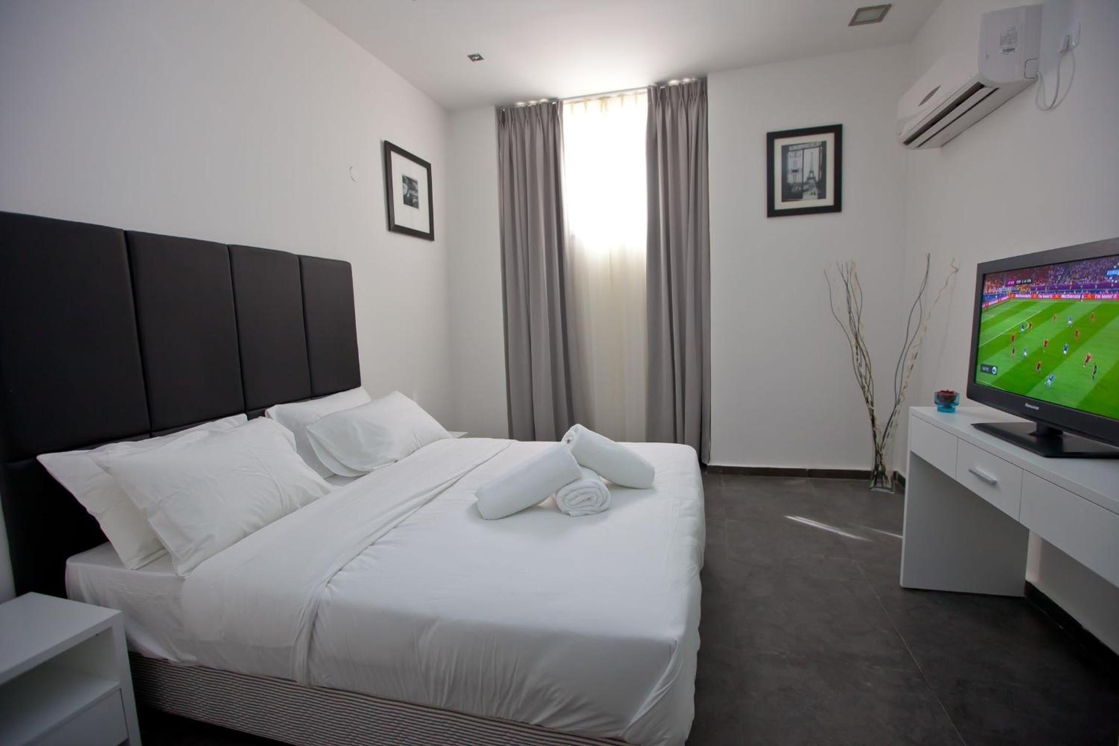 Une chambre d’hôtel avec un lit, un bureau, une télévision et des rideaux.