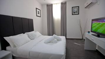 Une chambre d’hôtel avec un lit, un bureau, une télévision et des rideaux.