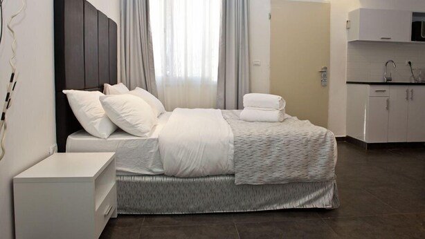 Habitació d'hotel moderna amb llit, taulell de nit i zona de cuina.