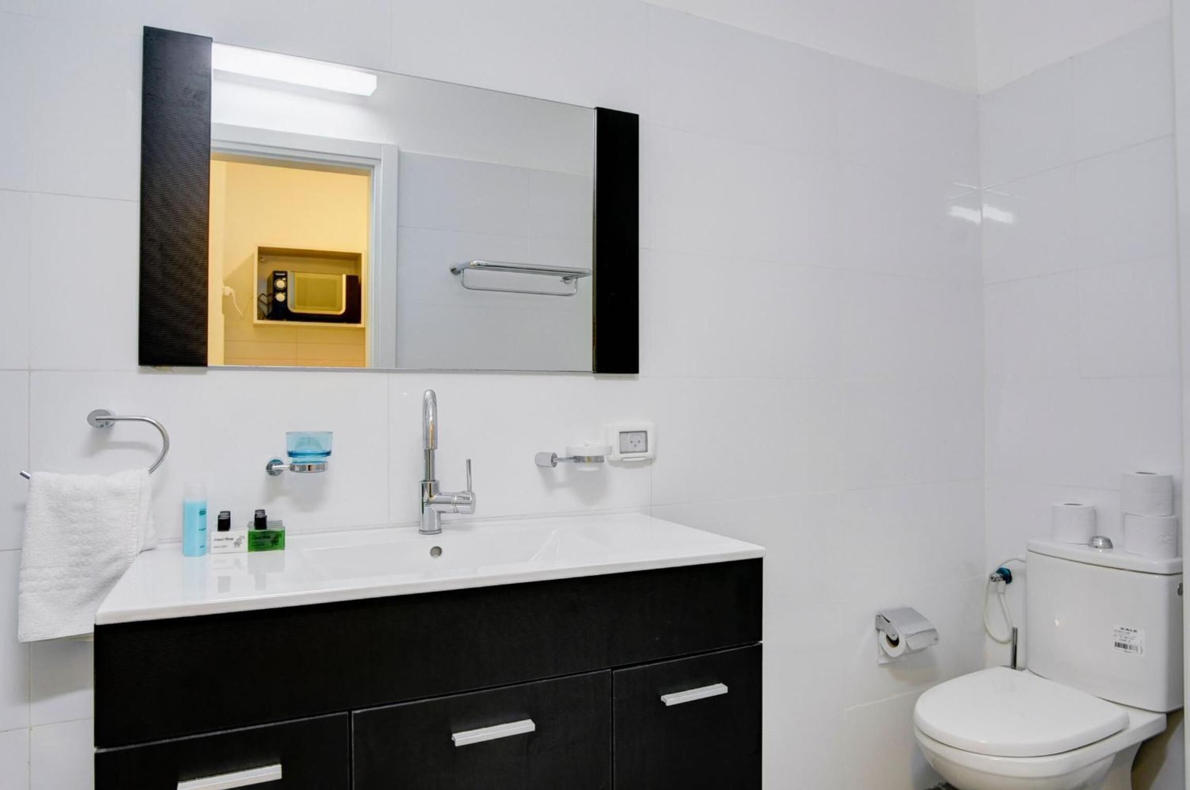 A modern bathroom with a white sink, black vanity, and a toilet.