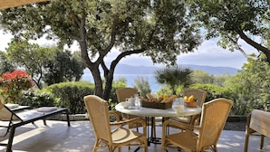 A round table with wicker chairs, a basket of fruit, and a view of the sea. - Résidence Arco Plage (Olmeto)