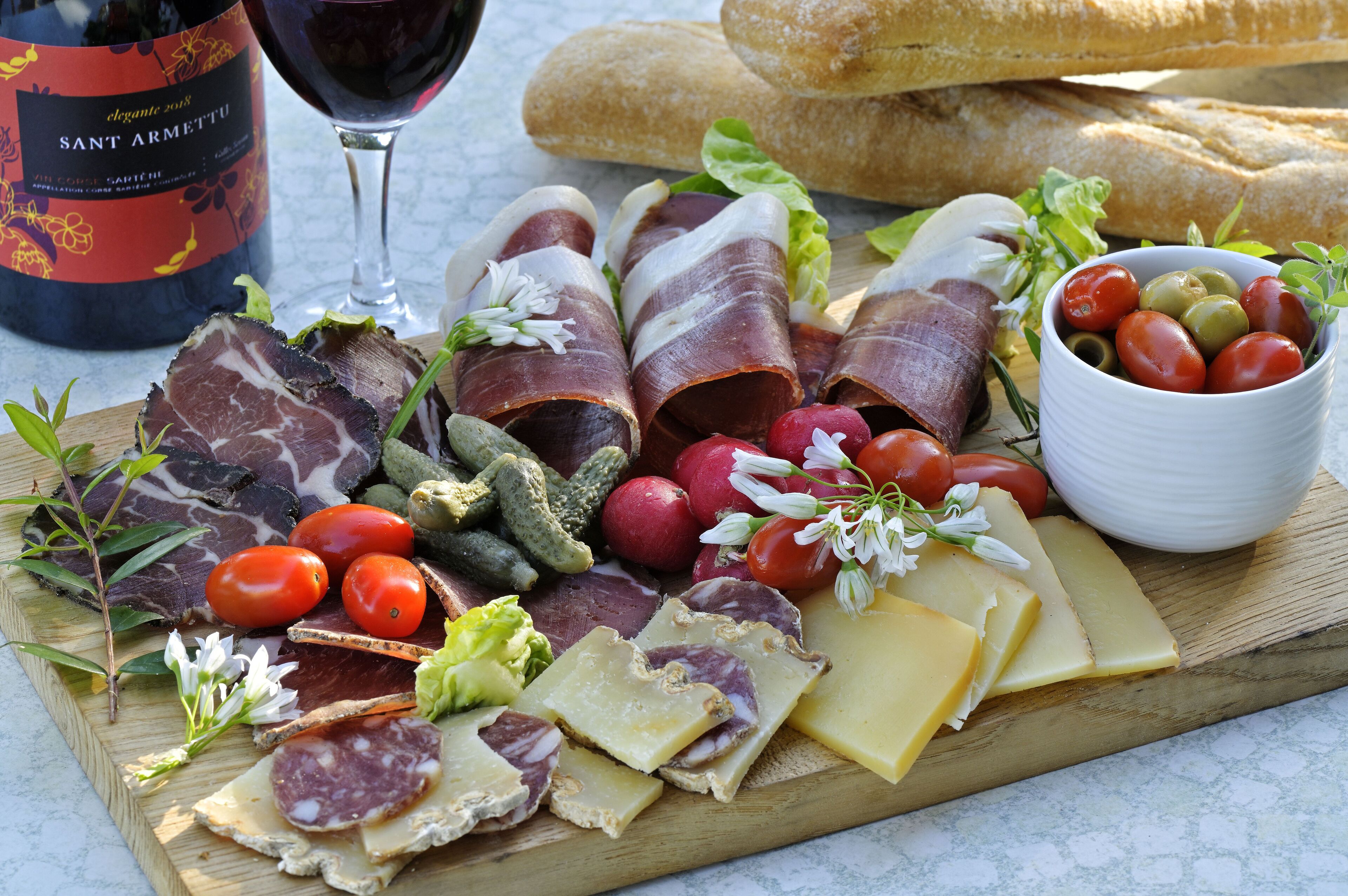 Une planche de charcuterie avec différentes sortes de viandes, de fromages et de légumes.
