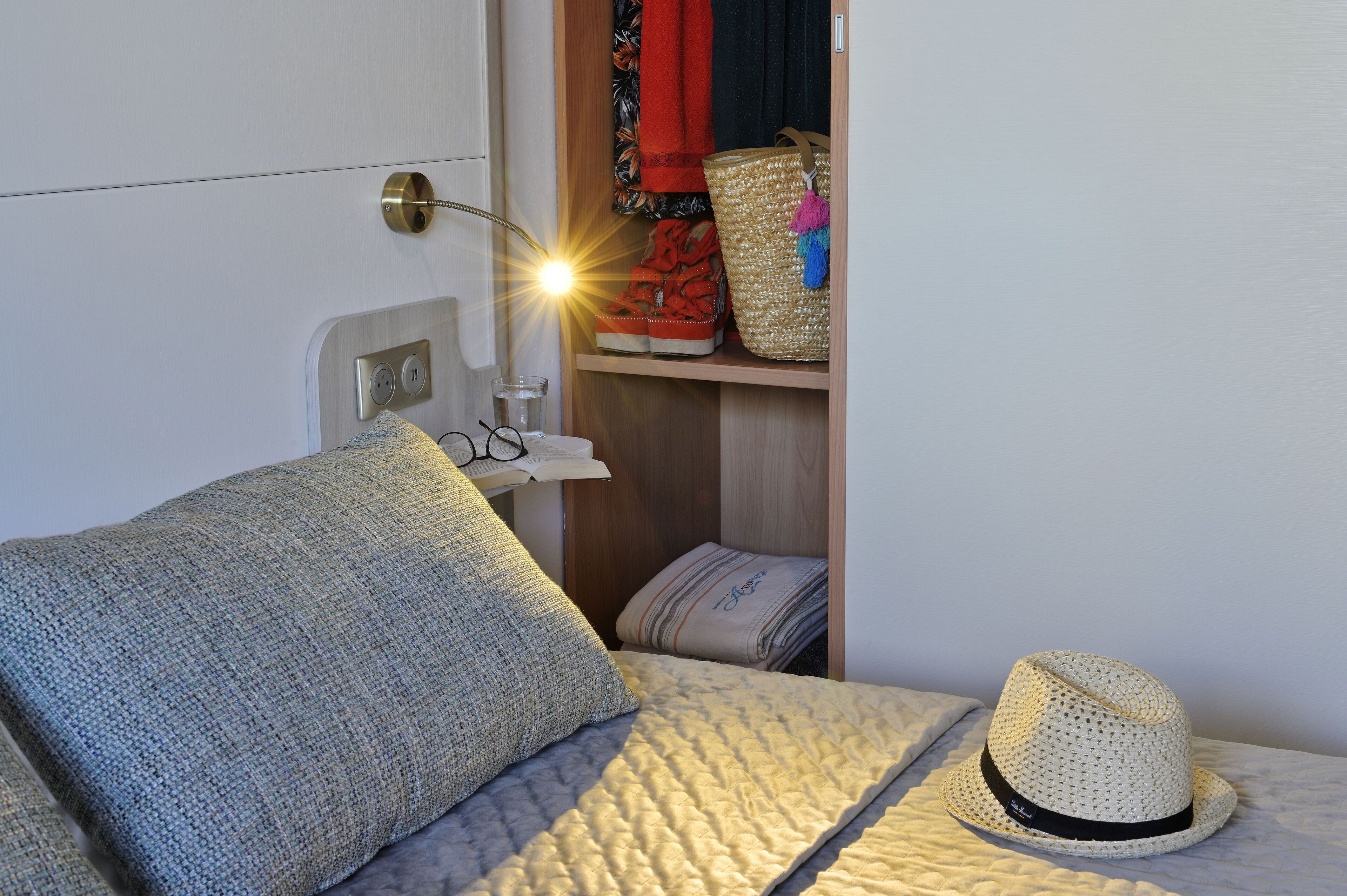Una cama bien hecha con un edredón acolchado y un sombrero de paja.