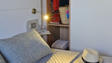 Una cama bien hecha con un edredón acolchado y un sombrero de paja.
