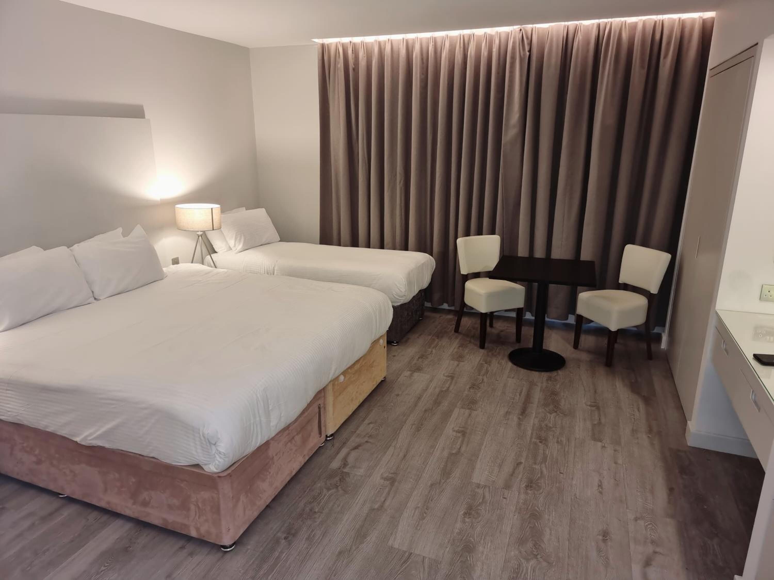 Habitació d'hotel amb dos llits, un escriptori, una cadira i una taula.