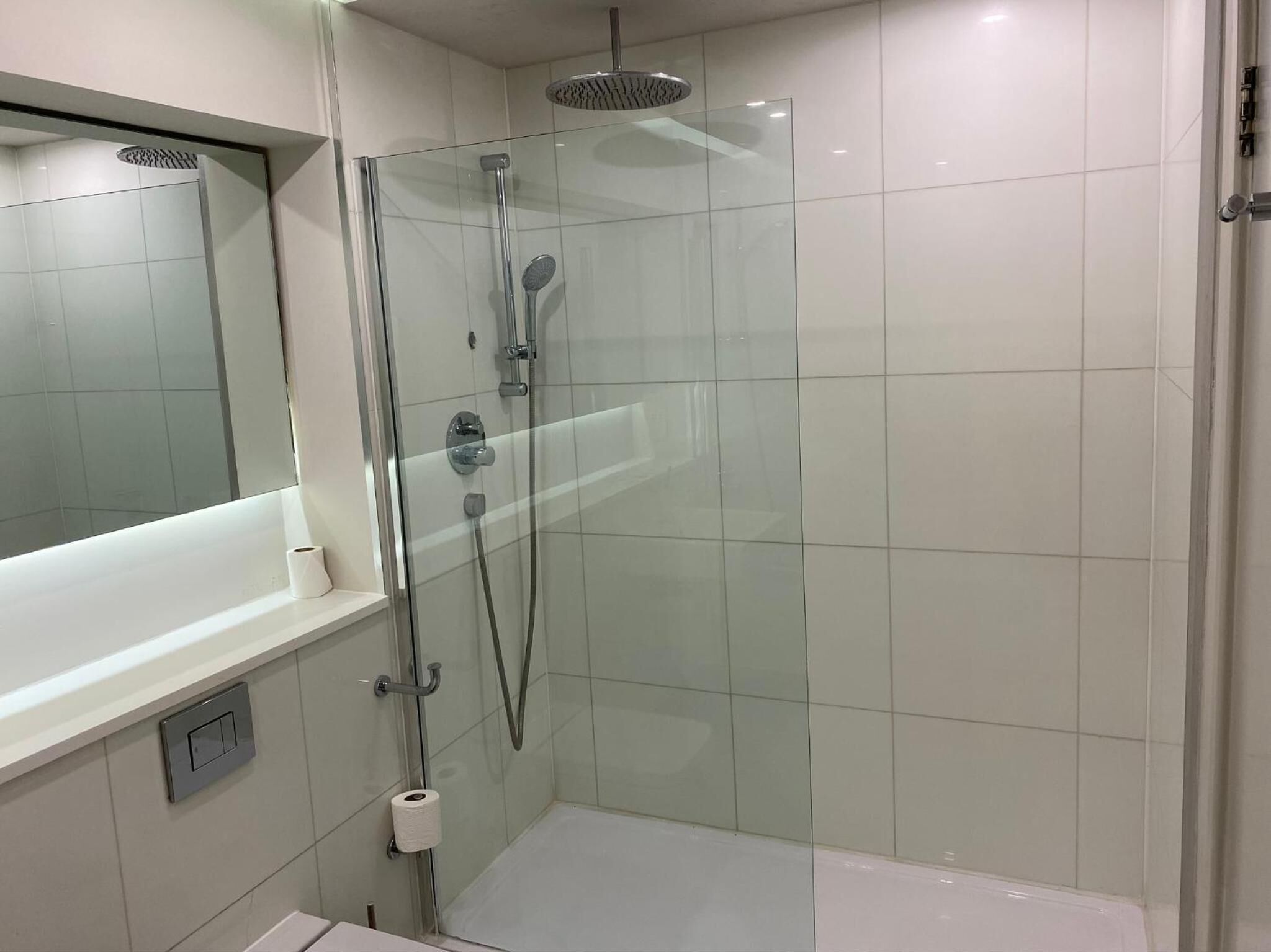 Un baño moderno con ducha envuelta en vidrio, inodoro y lavabo.