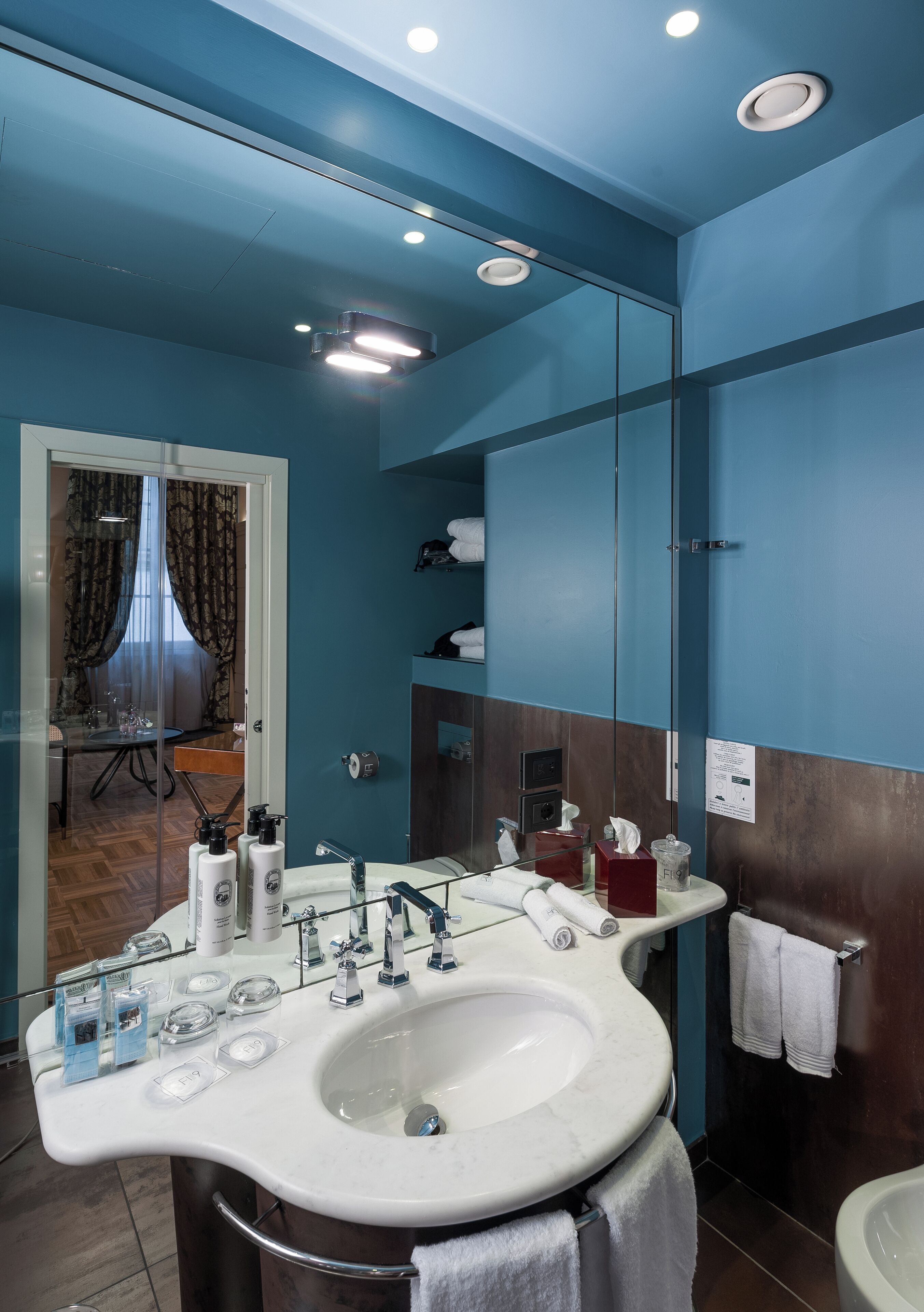 A modern bathroom with a large mirror, white sink, and a glass shower enclosure.