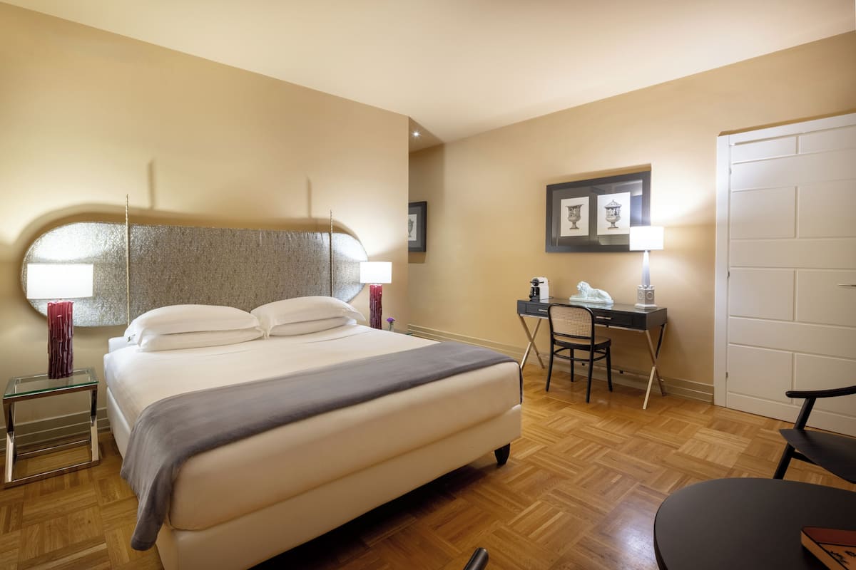 Habitación de hotel con cama, escritorio, silla y puerta.