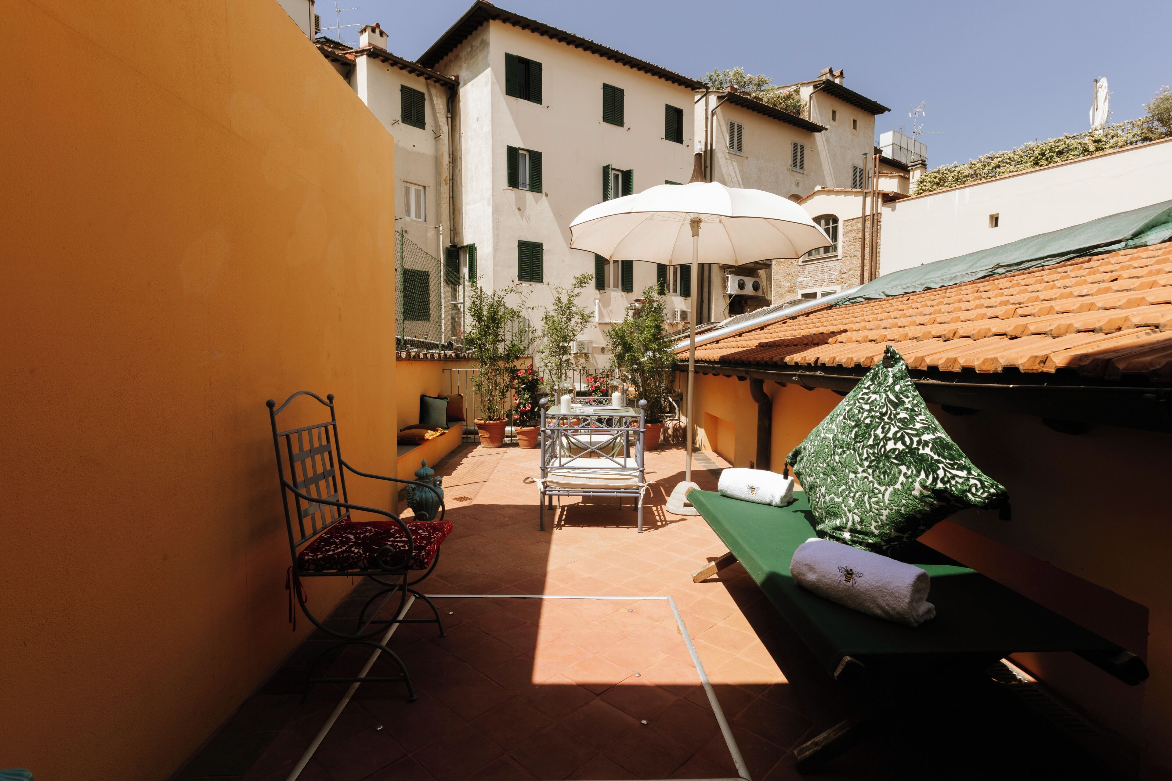 A courtyard with a table, chairs, an umbrella, and a bench.