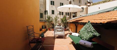 A courtyard with a table, chairs, an umbrella, and a bench.