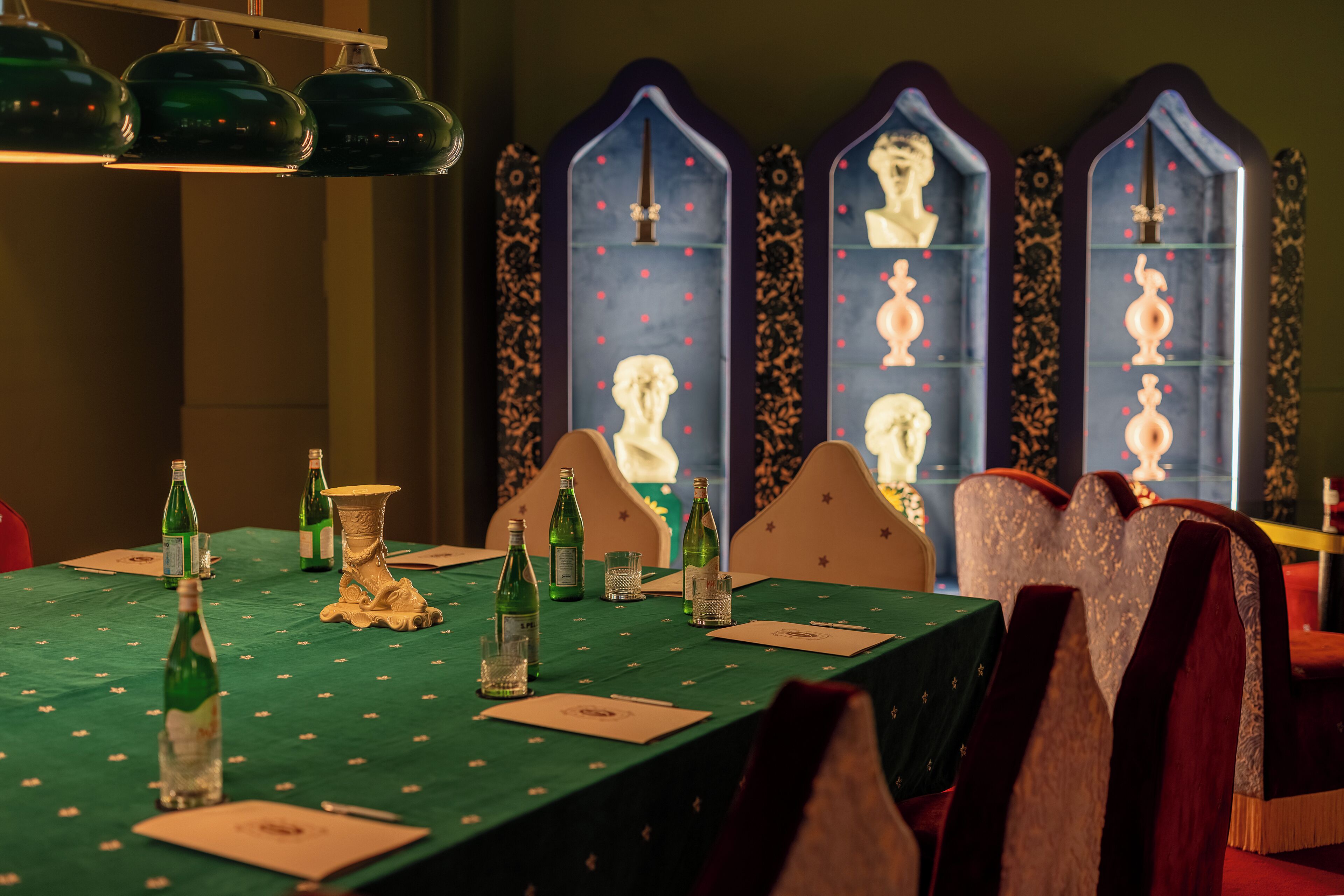 Een eettafel gedekt met een groene tafelkleed, flessen, glazen en een vaas.