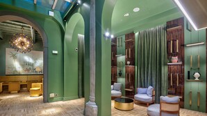 A lobby with green walls, wooden floors, and a central seating area with sofas and a coffee table. - Hotel Number Nine (Florence)
