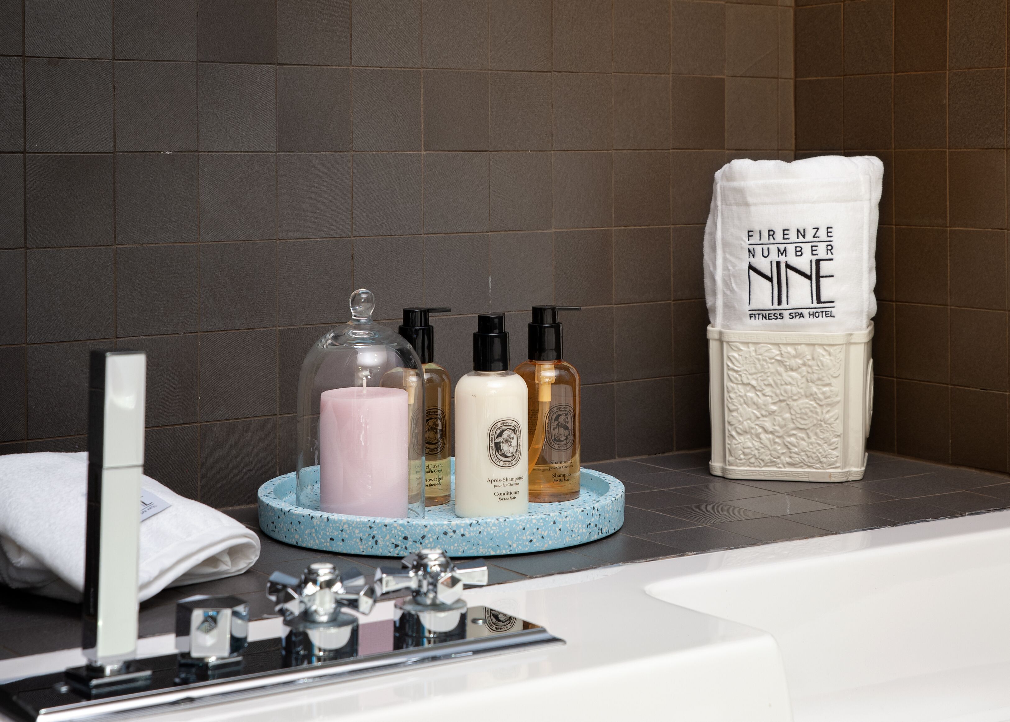 A bathroom with a bathtub, a towel rack, and toiletries on a blue tray.