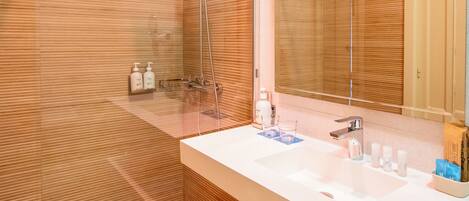 A modern bathroom with a glass shower enclosure, a white sink with a mirror, and wooden paneling on the walls.