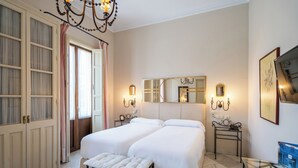 Une chambre avec deux lits, un grand miroir, des lampes de chevet, un banc et une table en verre.