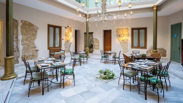 Un vaste atrium doté de hauts plafonds, d’un lustre central et de nombreuses tables à manger accompagnées de chaises.