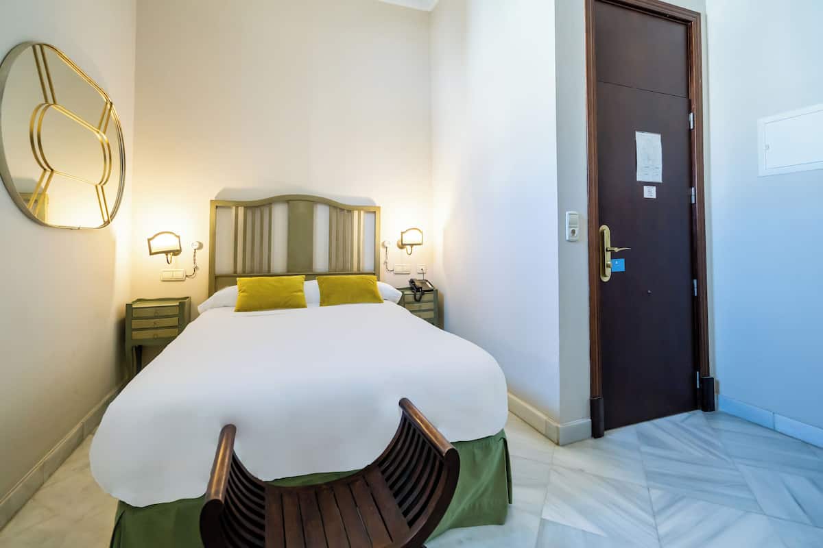 A neatly made bed with a wooden headboard, two bedside lamps, and a green nightstand.