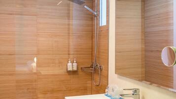 Ein modernes Badezimmer mit einer Duschwand aus Holz, einem weißen Waschbecken mit Spiegel und einem Handtuchhalter.