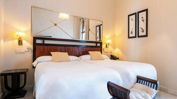 A hotel room with a large bed, two bedside lamps, a nightstand, a chair, a mirror, and framed artwork on the wall.