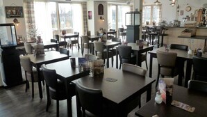 A restaurant with multiple tables and chairs, a television, and various decorations on the walls. - Hotel 't Zwaantje (Callantsoog)