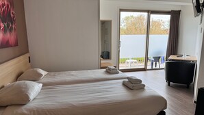 A hotel room with two beds, a balcony, a TV, and a desk with a chair. - Hotel 't Zwaantje (Callantsoog)