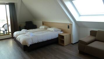 Une chambre d’hôtel moderne avec un grand lit, un canapé, un bureau et une fenêtre de toit.