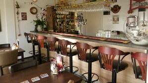 A bar area with a counter, stools, and a variety of bottles and glasses. - Hotel 't Zwaantje (Callantsoog)