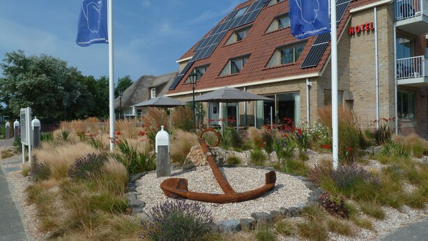 A hotel with a modern design, solar panels on the roof, and a unique sculpture in the garden. - Hotel 't Zwaantje (Callantsoog)
