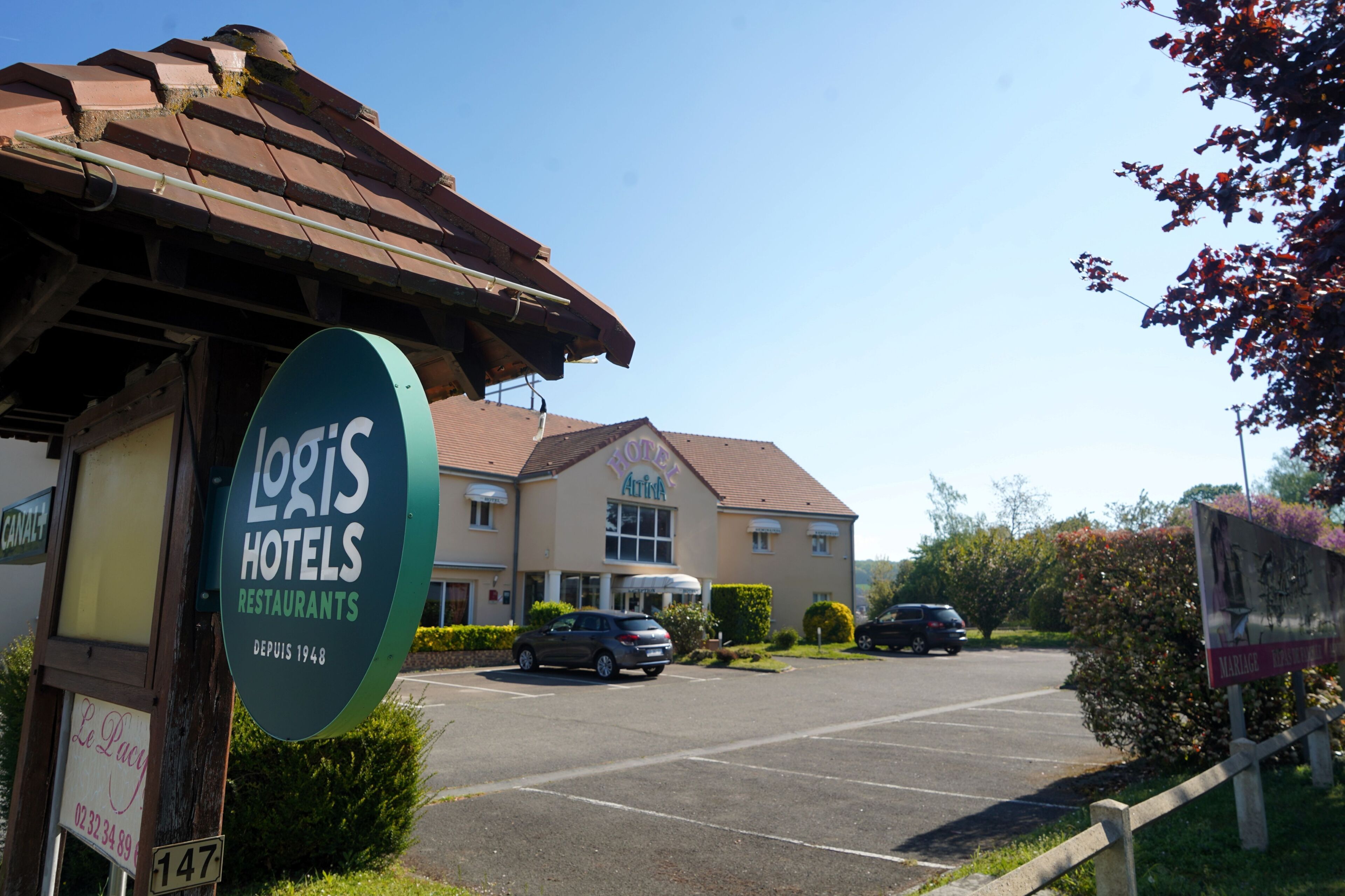 A hotel with a sign for 'Loris Hotels Restaurants' and a parking lot with cars.